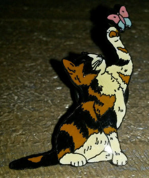 黒と白と茶色の猫が蝶のピンと遊んでいる