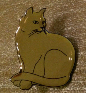 猫が誇らしげにポーズをとる銀色のピン